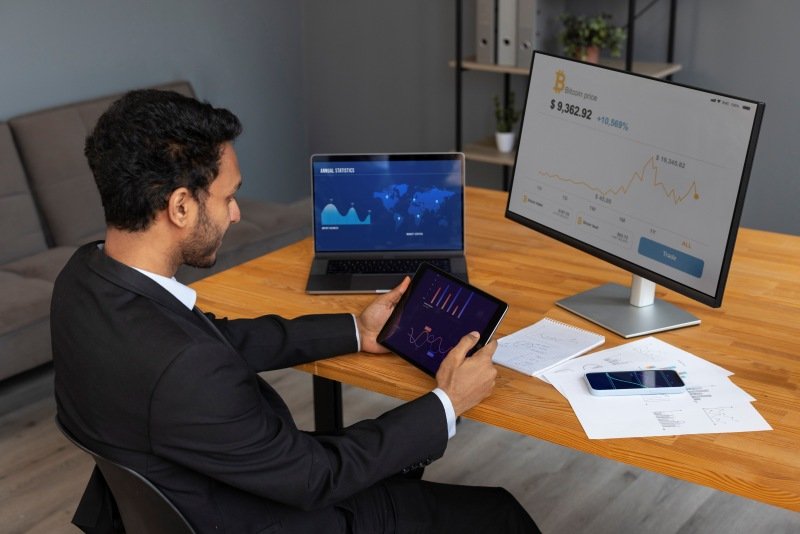 Investor reviewing cryptocurrency charts and market data on multiple screens using Lessinvest.com Crypto guide.